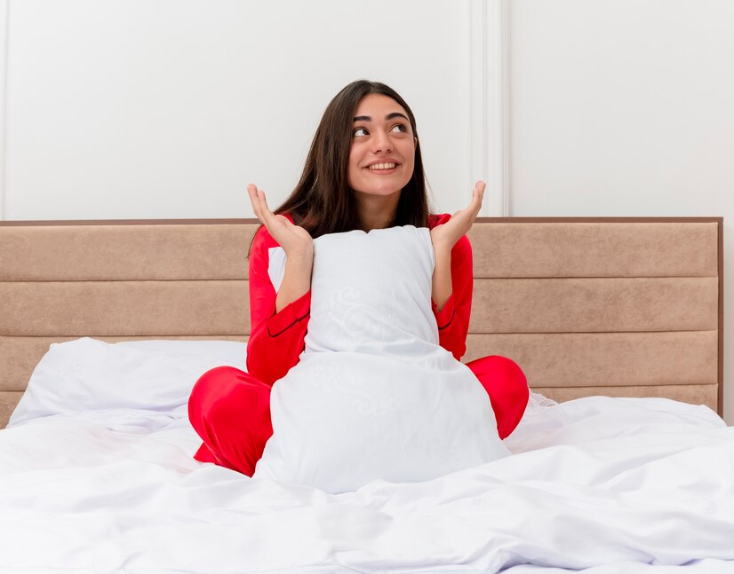 files/pleased-young-beautiful-woman-red-pajamas-sitting-bed-with-pillow-looking-up-smiling-with-happy-face-enjoying-weekend-bedroom-interior_141793-102541.jpg